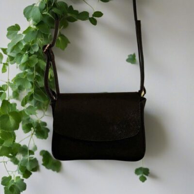 Svart veske mot hvit bakgrunn og blomster